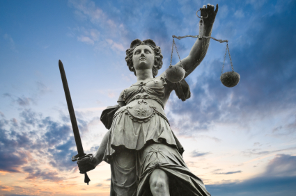 justice statue with sword and scale. cloudy sky in the backgroun alternate text for this image