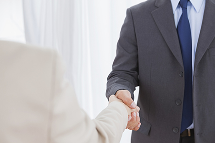 New partners shaking hands in bright office alternate text for this image