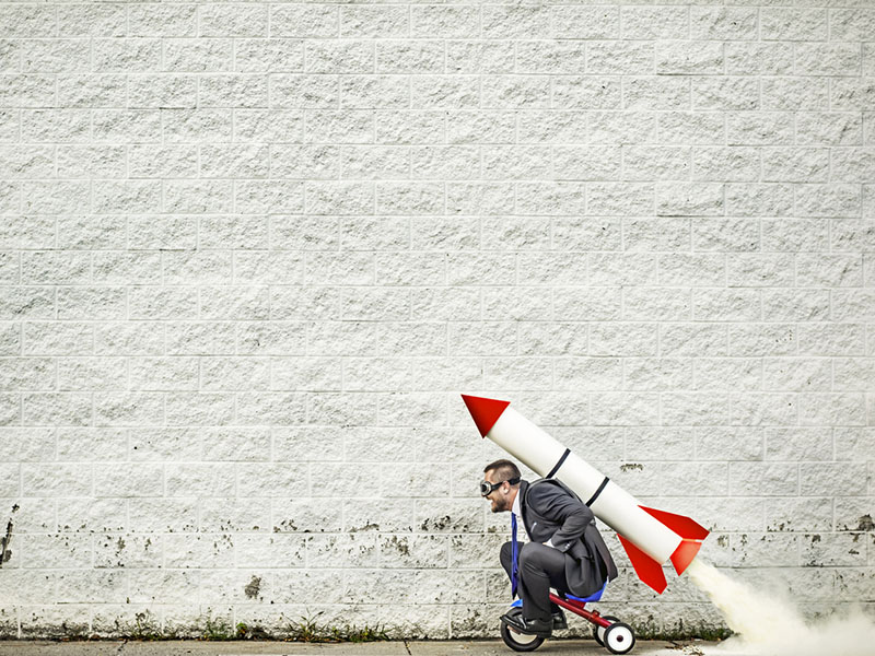 Homme d'affaires avançant sur un tricycle propulsé par une fusée.