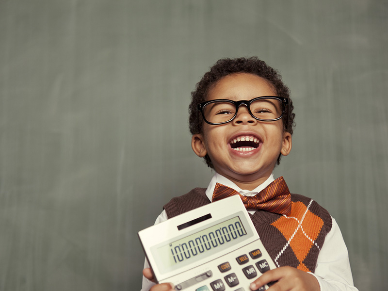 Jeune garçon éclatant de rire et tenant une calculatrice.