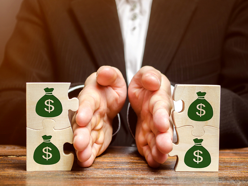 Businessman separates the wooden puzzle with a picture of money. The concept of financial management and distribution of funds. Saving and investing. Property division. Divorce and legal services alternate text for this image