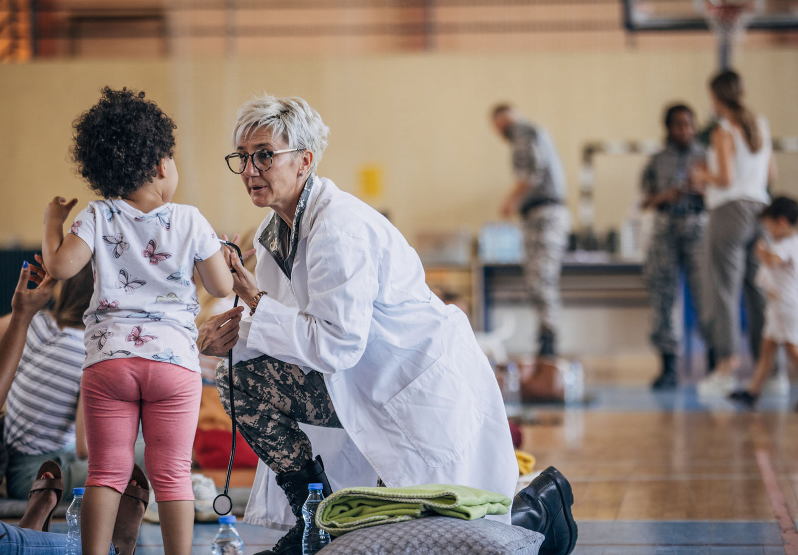 Groupe de personnes diverses, soldats apportant une aide humanitaire aux civils dans le gymnase d'une école, après une catastrophe naturelle survenue dans la ville.
