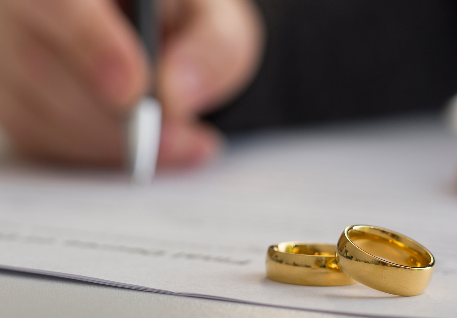 Mains de l'épouse, du mari signant le jugement de divorce, la dissolution, l'annulation du mariage, les documents de séparation légale, le dépôt des documents de divorce ou l'accord prénuptial préparé par l'avocat. Anneau de mariage.