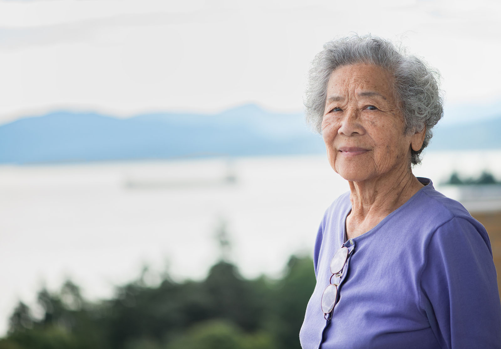 Portrait d'une femme chinoise en bonne santé, âgée de 80 ans, vivant de façon indépendante et regardant la vue depuis son appartement donnant sur English Bay à Vancouver, en Colombie-Britannique, au Canada.