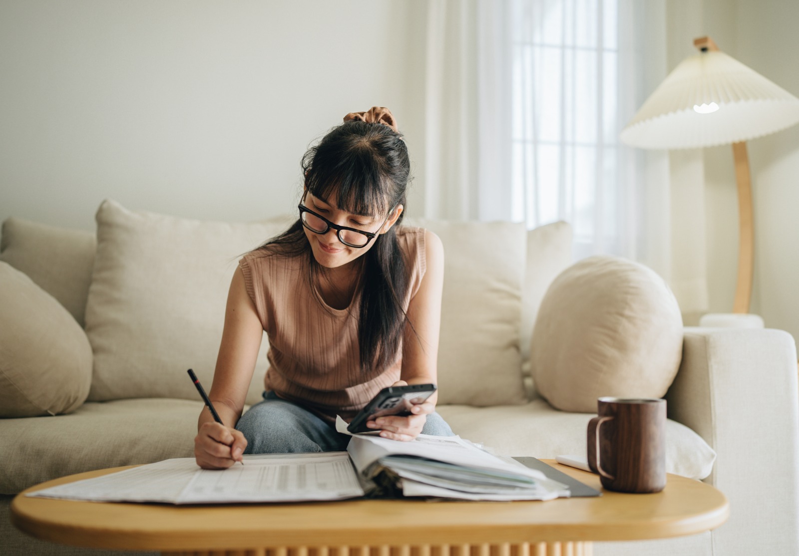 Femme asiatique planifiant le budget et utilisant la calculatrice sur smartphone.