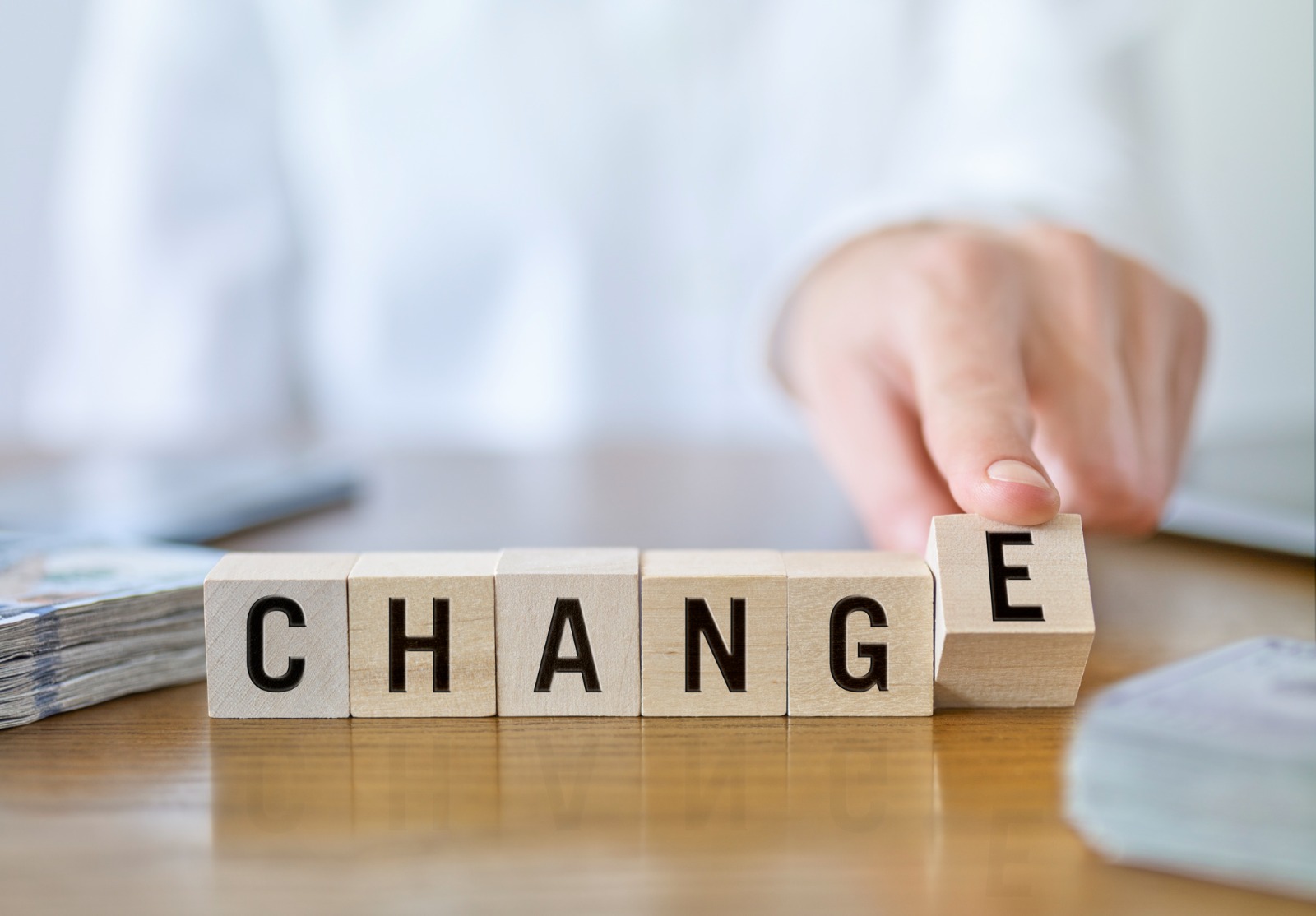 Une main qui place des cubes en bois sur une table pour former le mot « change »