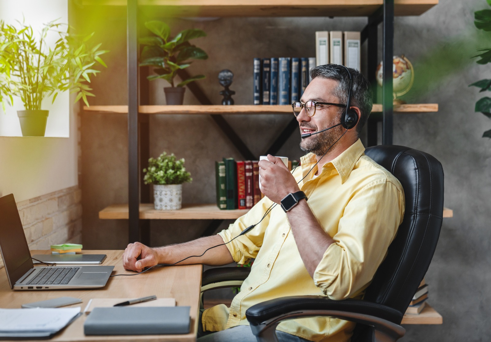 Un homme d'affaire faisant du télétravail, mais prenant une pause avec un café.