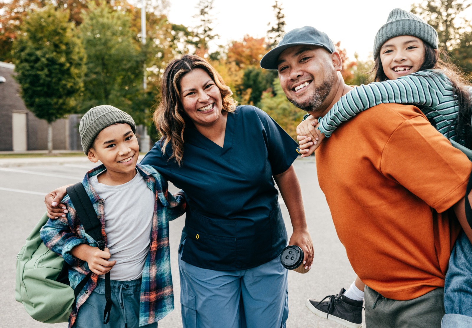 Une famille de 4 personnes avec les parents et les enfants dans la rue. Ils sont tous souriants.
