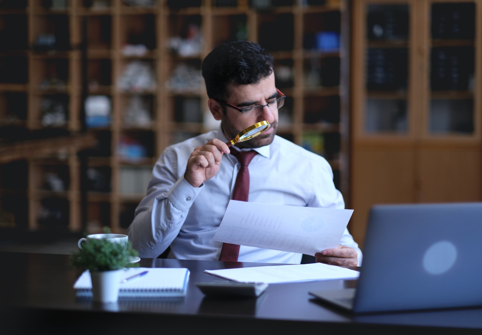 Un homme d’affaires examine les valeurs statistiques à la loupe.
