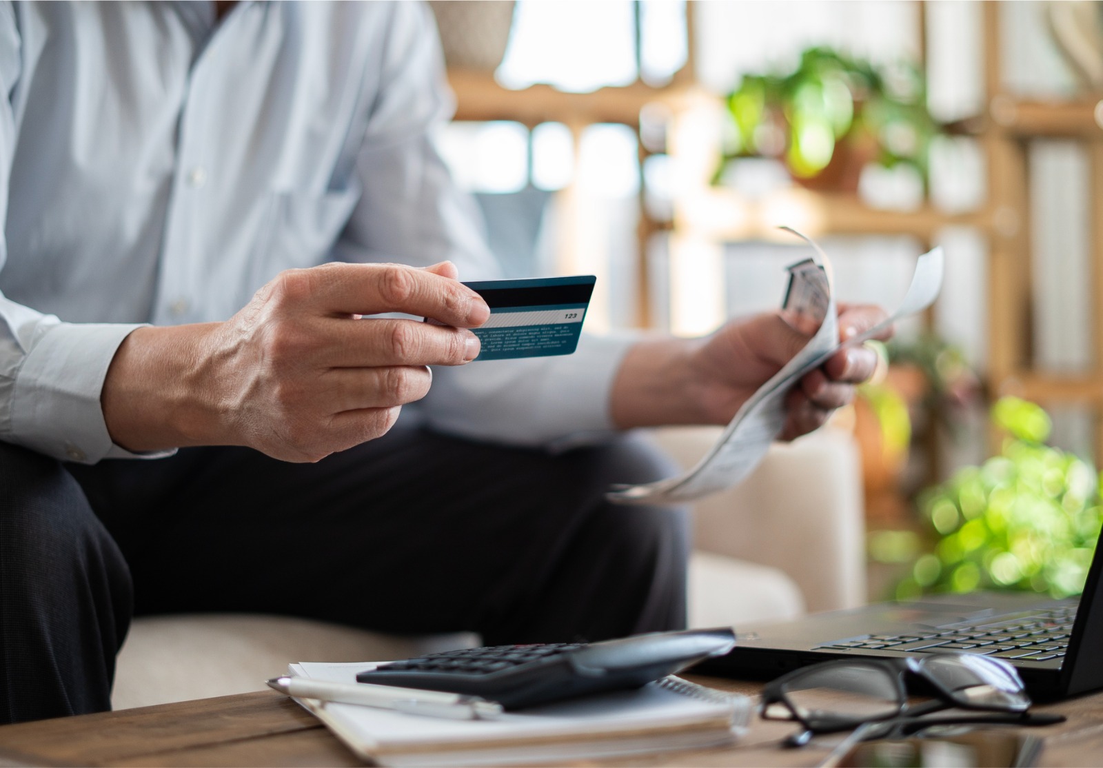Un homme âgé en gros plan paie ses factures avec une carte de crédit.