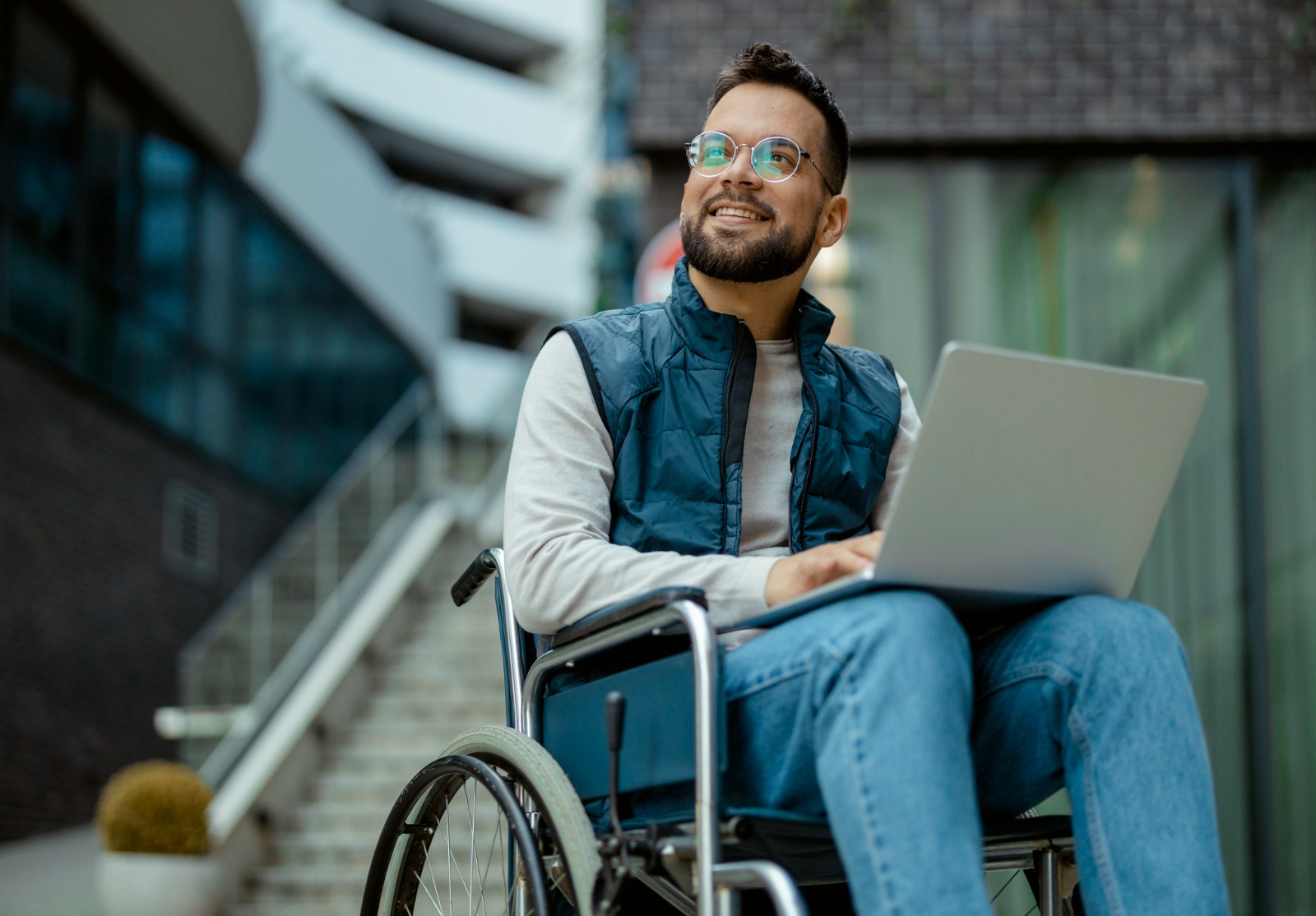 Homme handicapé avec ordinateur portable en fauteuil roulant à l’extérieur