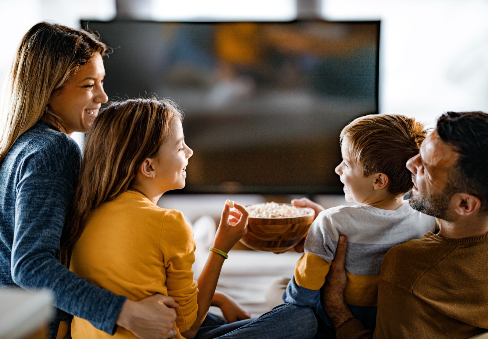 Famille heureuse mangeant le pop-corn tout en regardant la TV à la maison.