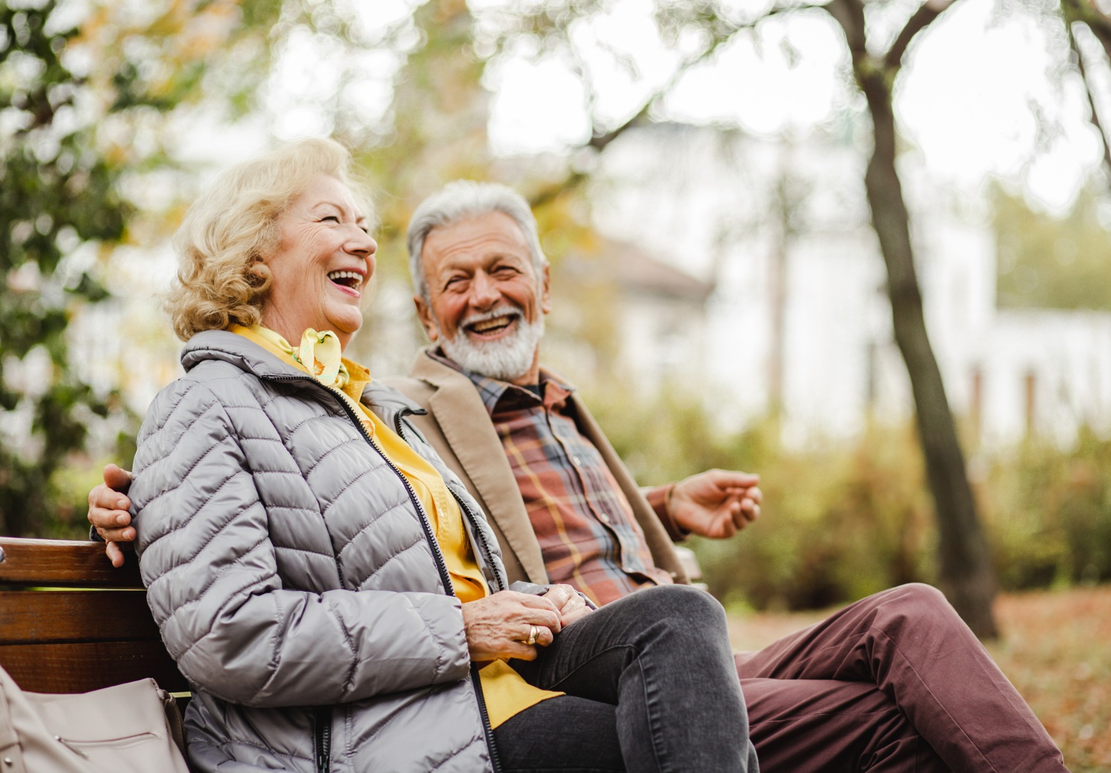 Couples aînés heureux s’asseyant sur le banc dans le stationnement.