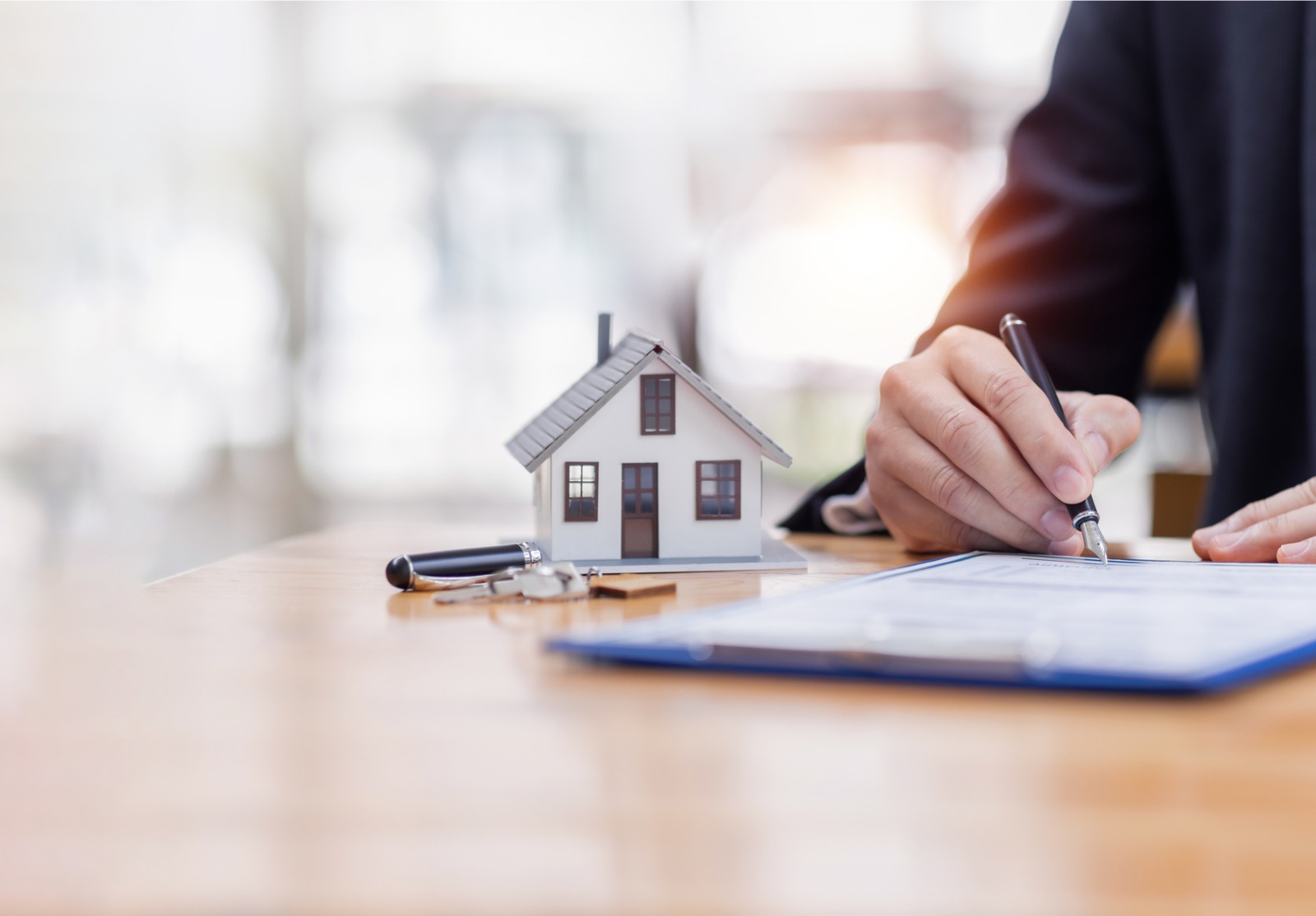 Modèle de maison avec homme d’affaires signe un contrat d’achat ou une hypothèque pour une assurance habitation d’achat et de vente concernant le prêt hypothécaire Concept immobilier, espace de copie pour le texte de l’éditeur.