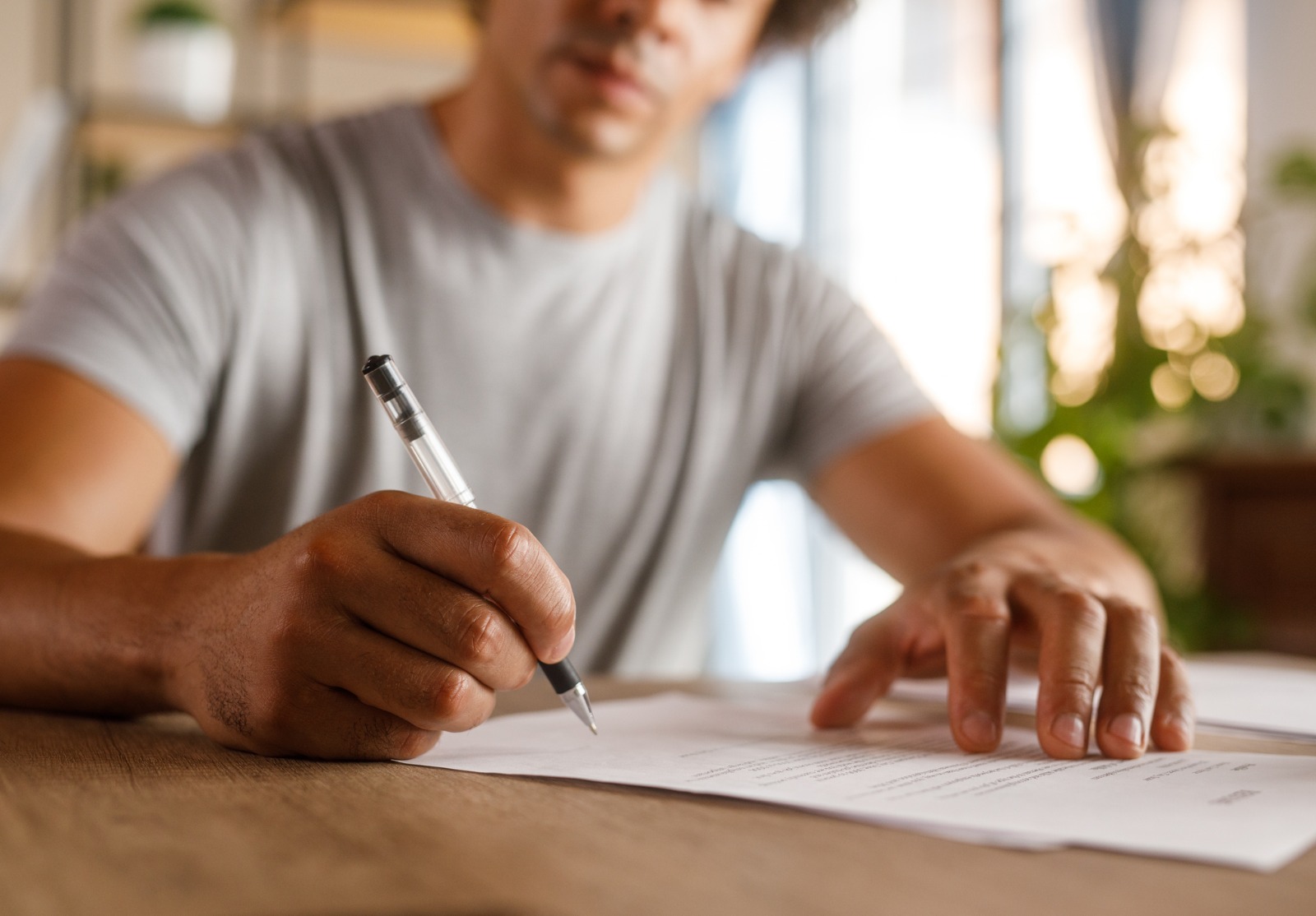 Homme assis à table, examinant des documents et signant des contrats