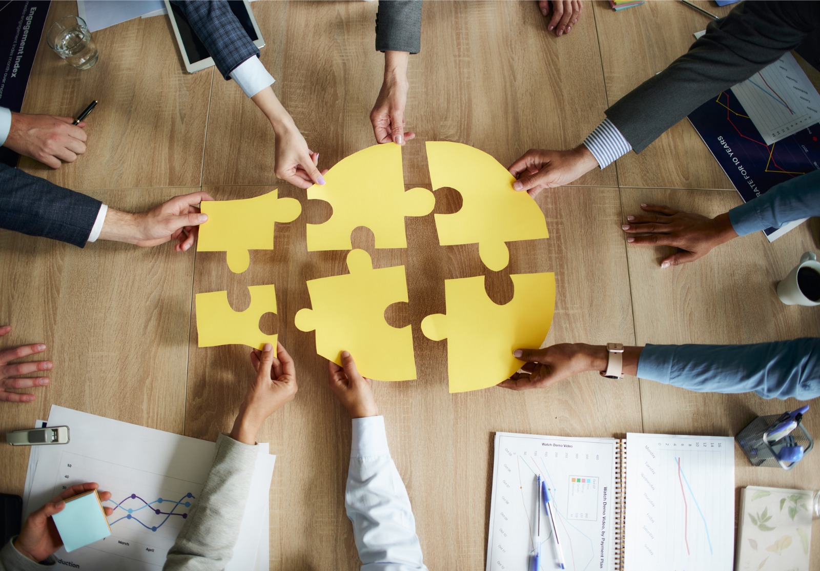 Connexion parfaite sur réunion d’affaires! Plusieurs personnes autour d'une table qui mettent ensemble des pièces de puzzle ce qui fait une ampoule.