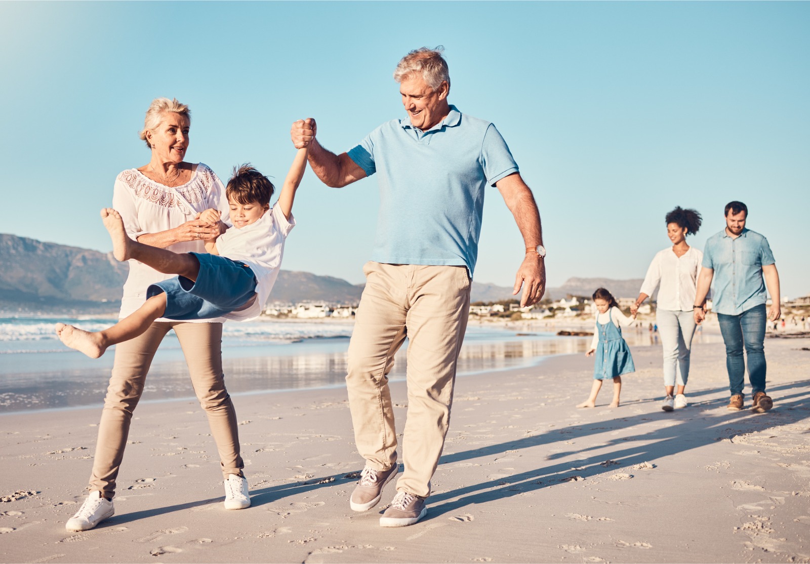 Balançoire, grands-parents et un enfant marchant sur la plage lors de vacances en famille, de vacances ou d’aventure en été. Jeune garçon enfant tenant la main d’un homme et d’une femme âgés à l’extérieur avec une énergie ou un jeu amusant.