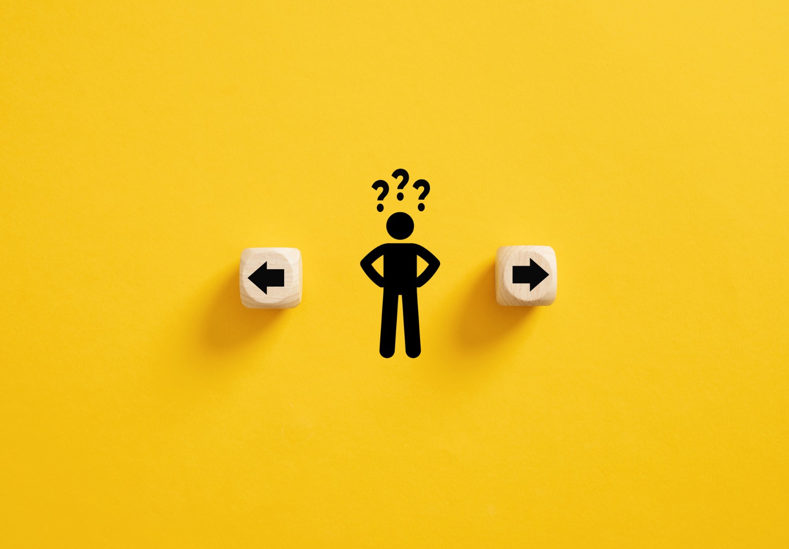 Prise de décision et choix de la bonne voie. Confusion quant au choix de la direction à prendre. Stickman avec des points d’interrogation debout entre les cubes en bois avec des symboles de flèche.
