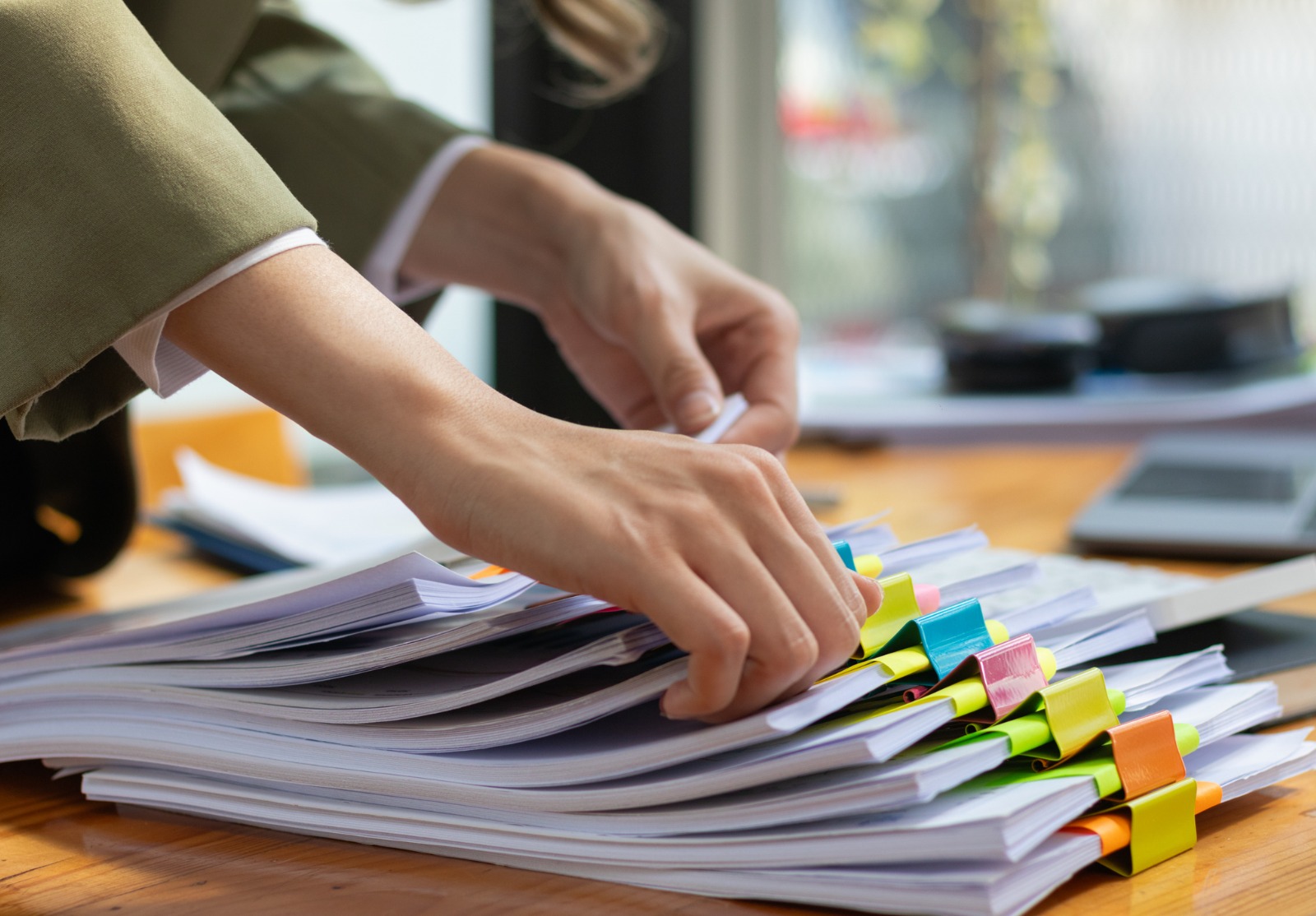 La secrétaire fouille dans une pile de documents importants sur la table du bureau, les livre au gestionnaire pour qu’il les présente à temps lors de la réunion. Notion de difficulté à trouver de l’information à partir de piles de documents.