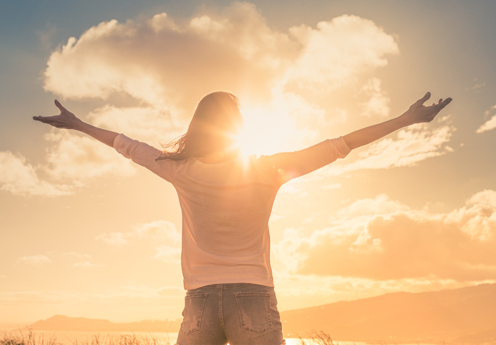 Jeune femme avec les mains levées la lumière du soleil du matin trouver le bonheur, la paix et l’espoir dans la nature.