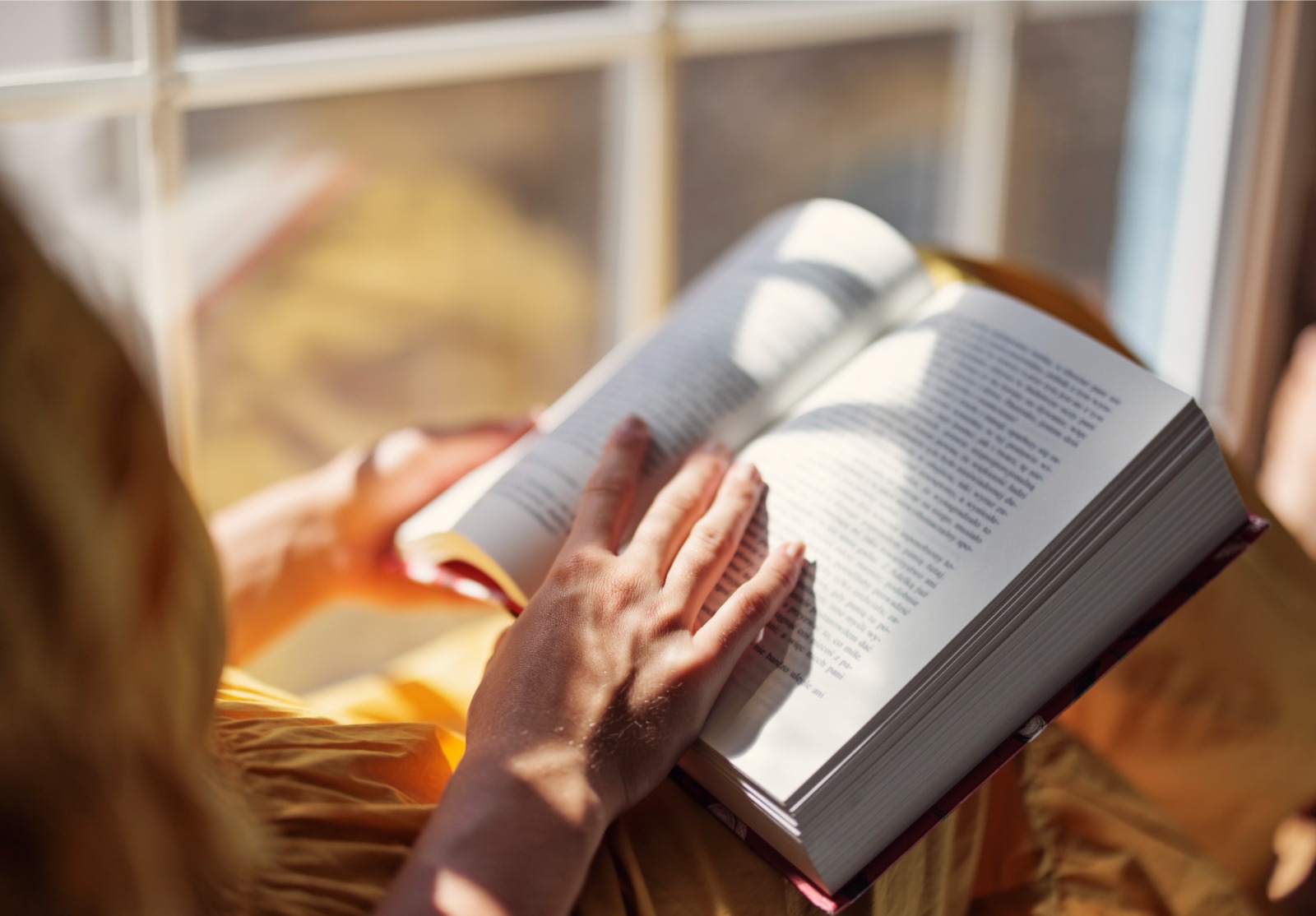 Une jeune fille assise en train de lire un livre.