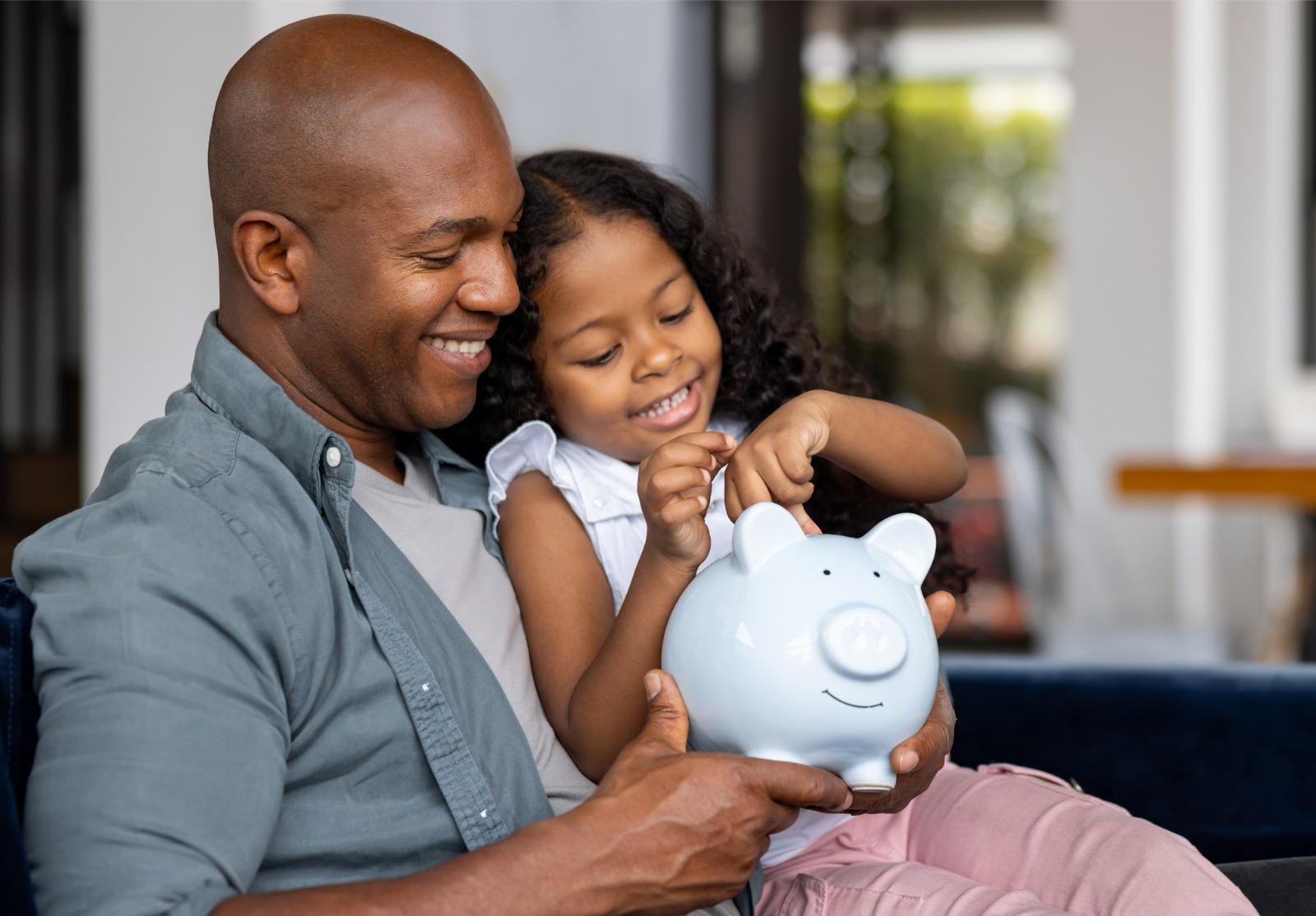 Père et fille économisant de l’argent dans une tirelire.