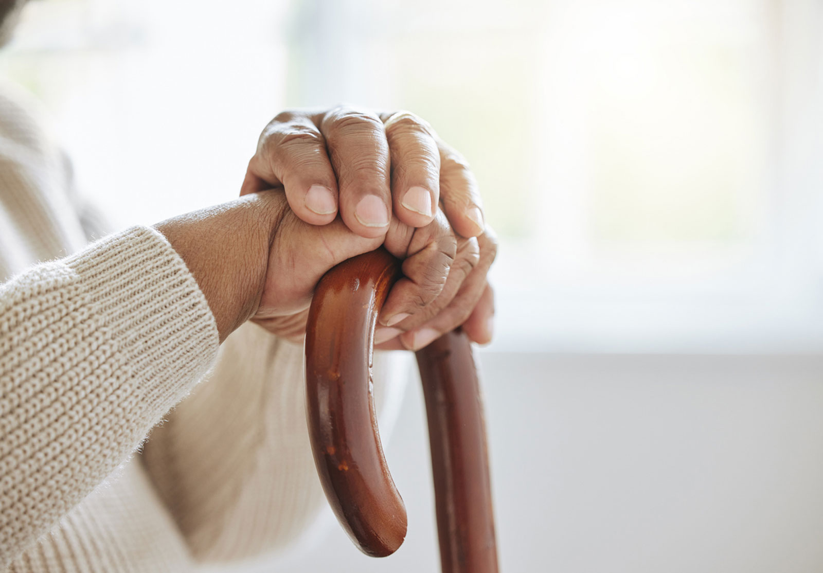 Des mains d'une personne d'un certain âge, posées sur une canne