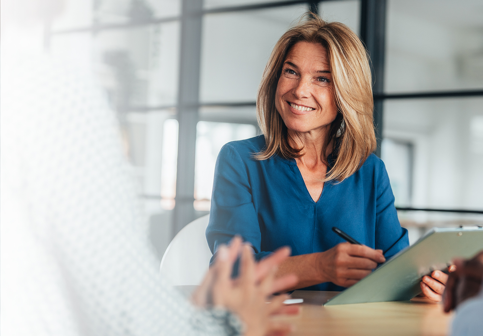 Une femme d'affaires en conversation avec un collègue autour d'une table de conférence.