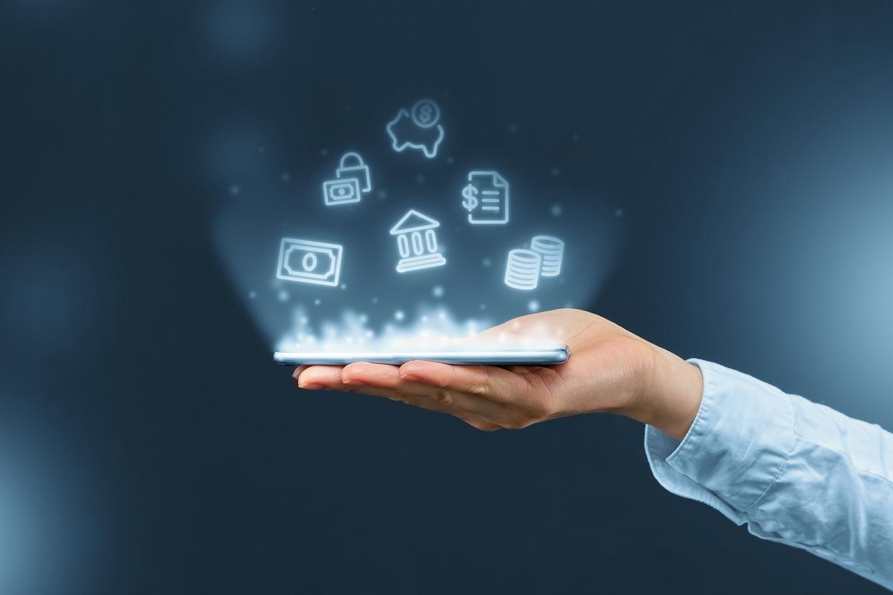 Main tenant un smartphone avec des icônes holographiques de banque et de finance flottant au-dessus (sécurité, argent, banque, pièces de monnaie). Représentation abstraite des services financiers numériques.