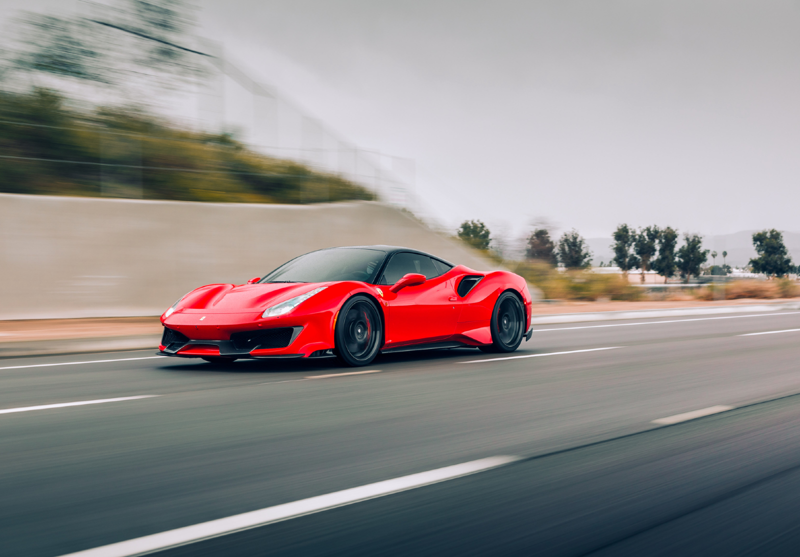 Une Ferrari sur une route. Le paysage autour est flou, comme si la voiture allait très vite.